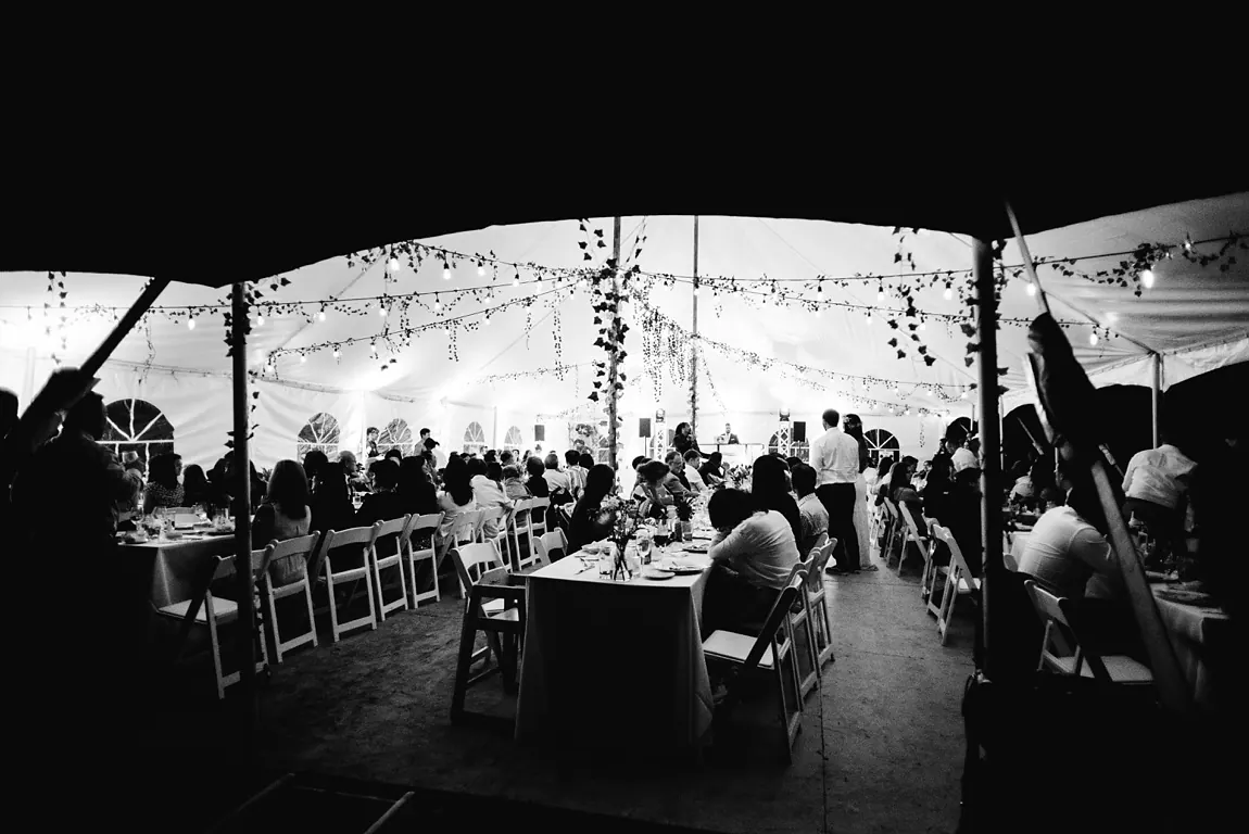 Invités attablés sous le chapiteau illuminé, noir et blanc