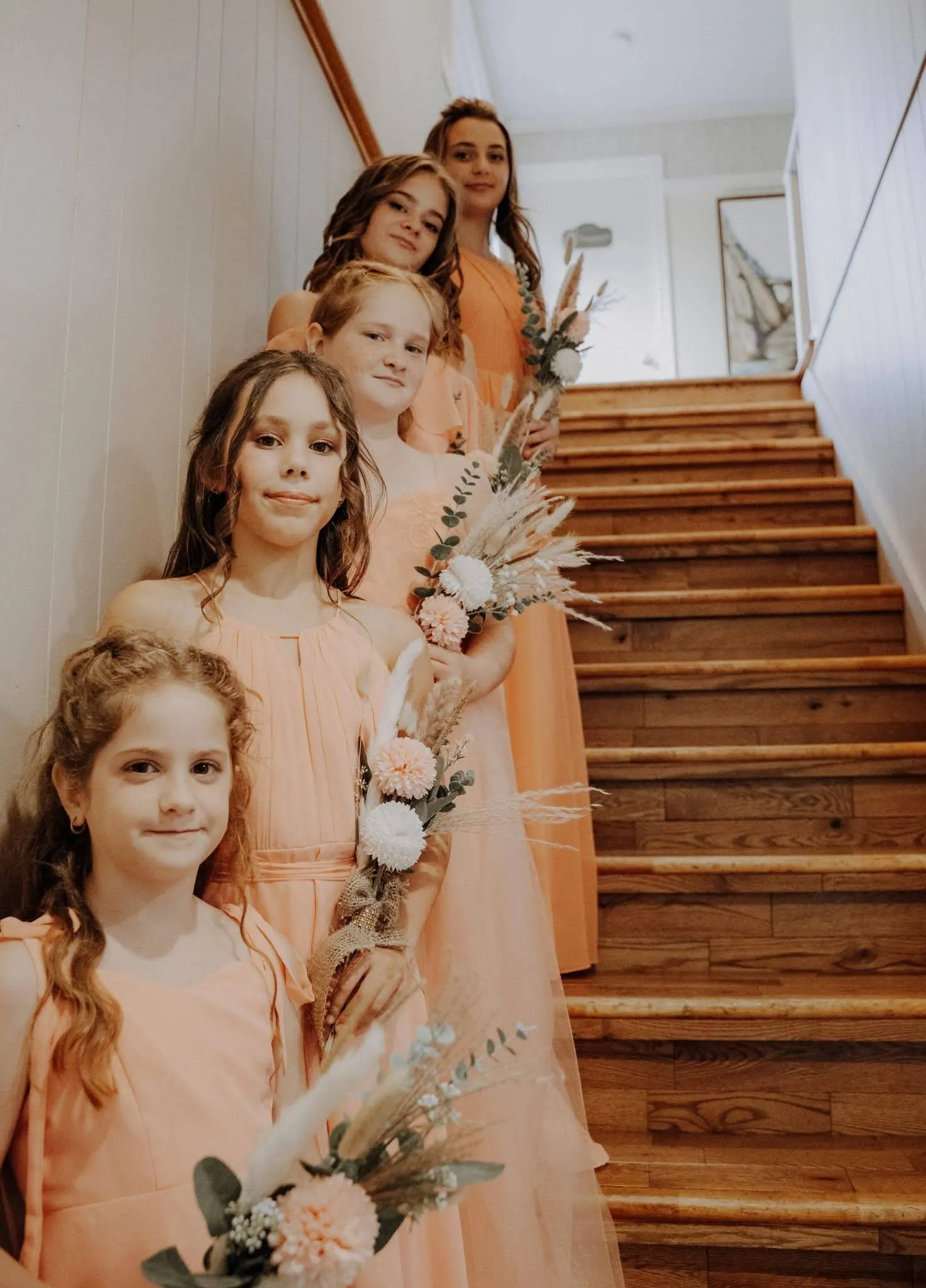 Les demoiselles d'honneur en robes pêche dans l'escalier du chalet