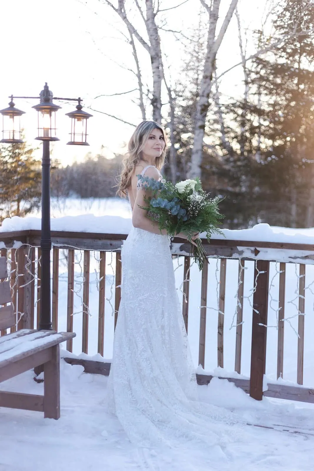La mariée sur la terrasse enneigée, lampadaire et guirlandes lumineuses