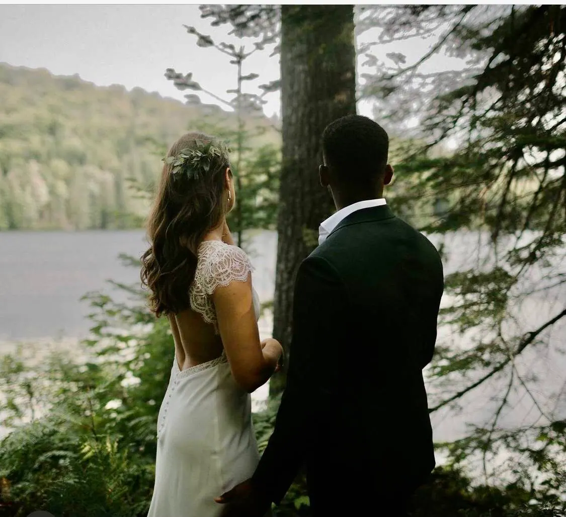 Les mariés, de dos, regardent le lac depuis la forêt