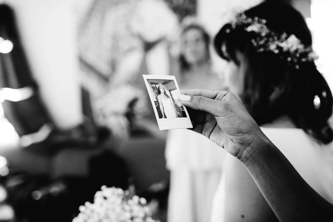 La mariée regarde un polaroid d'elle, noir et blanc